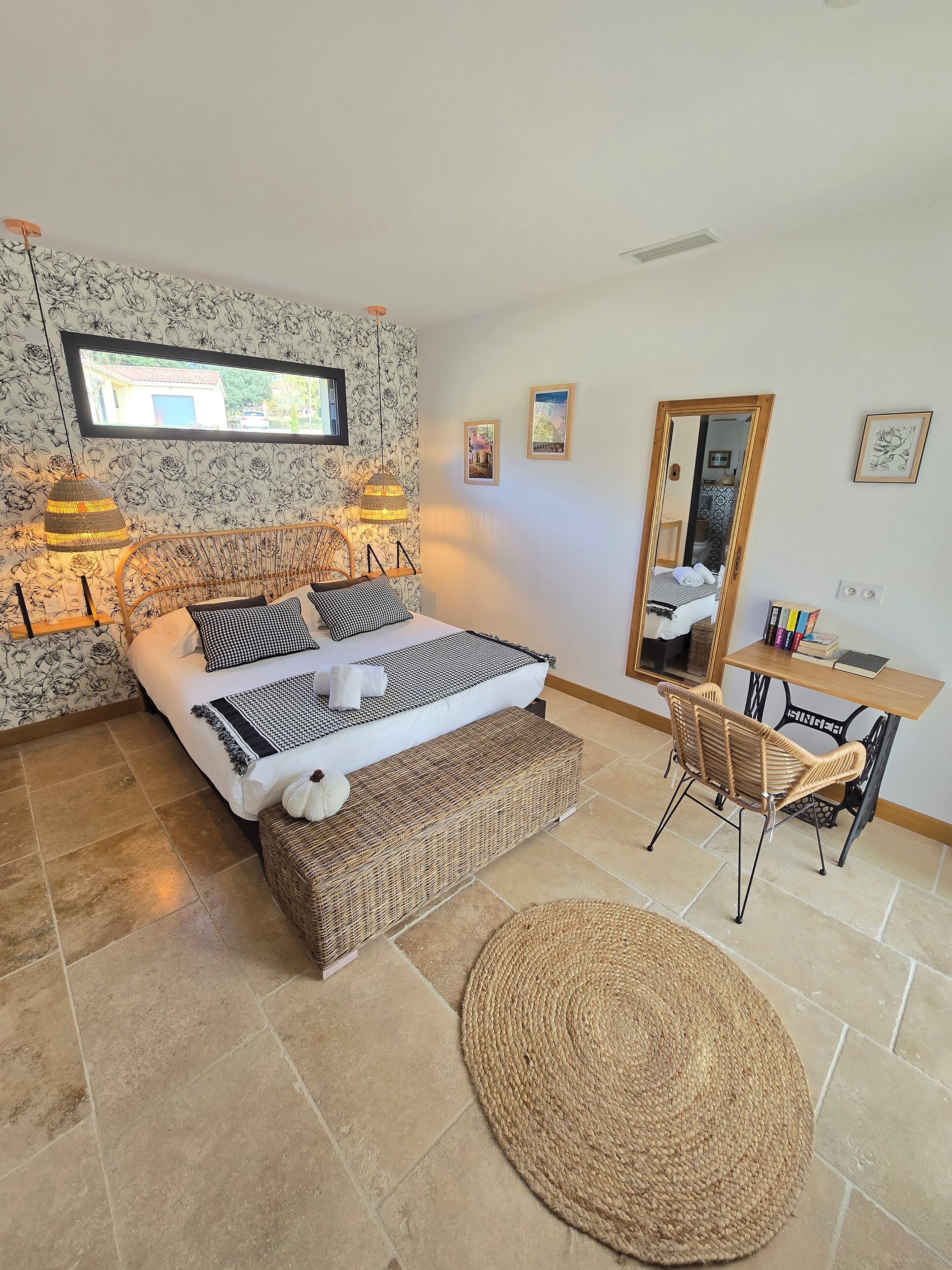 A bedroom with a bed, bedside lamps, a desk, a chair, and a large mirror.