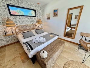 Une chambre d’hôtel avec un lit, un grand miroir et un téléviseur fixé au mur.