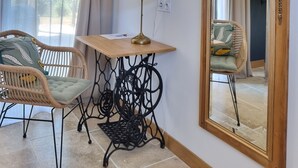 A room with a large mirror, a wicker chair, a small table with a lamp, and a window with curtains. - LOU MIYA - Gîte Périgourdin 5kms from SARLAT, Air conditioning, Jacuzzi SPA WELLIS (Carsac-Aillac)