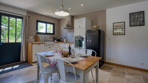 Una cocina moderna con armarios blancos, una mesa de comedor de madera y un refrigerador negro.