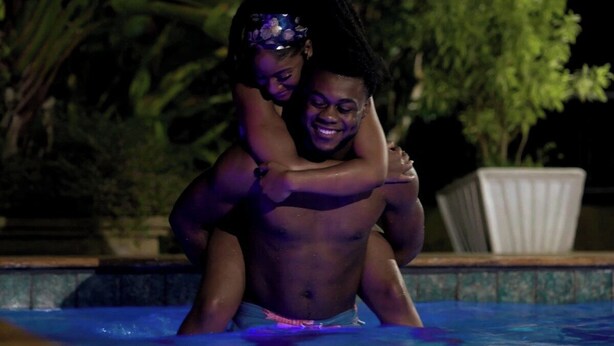 A person in a swimming pool with another person standing behind them.