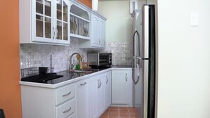 A kitchen with white cabinets, a stainless steel refrigerator, and a tiled backsplash.
