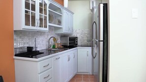 A kitchen with white cabinets, a stainless steel refrigerator, and a tiled backsplash.