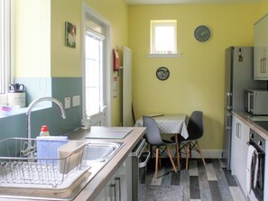 Et kompakt køkken med vask, et lille spisebord, stole, et køleskab og en mikrobølgeovn.