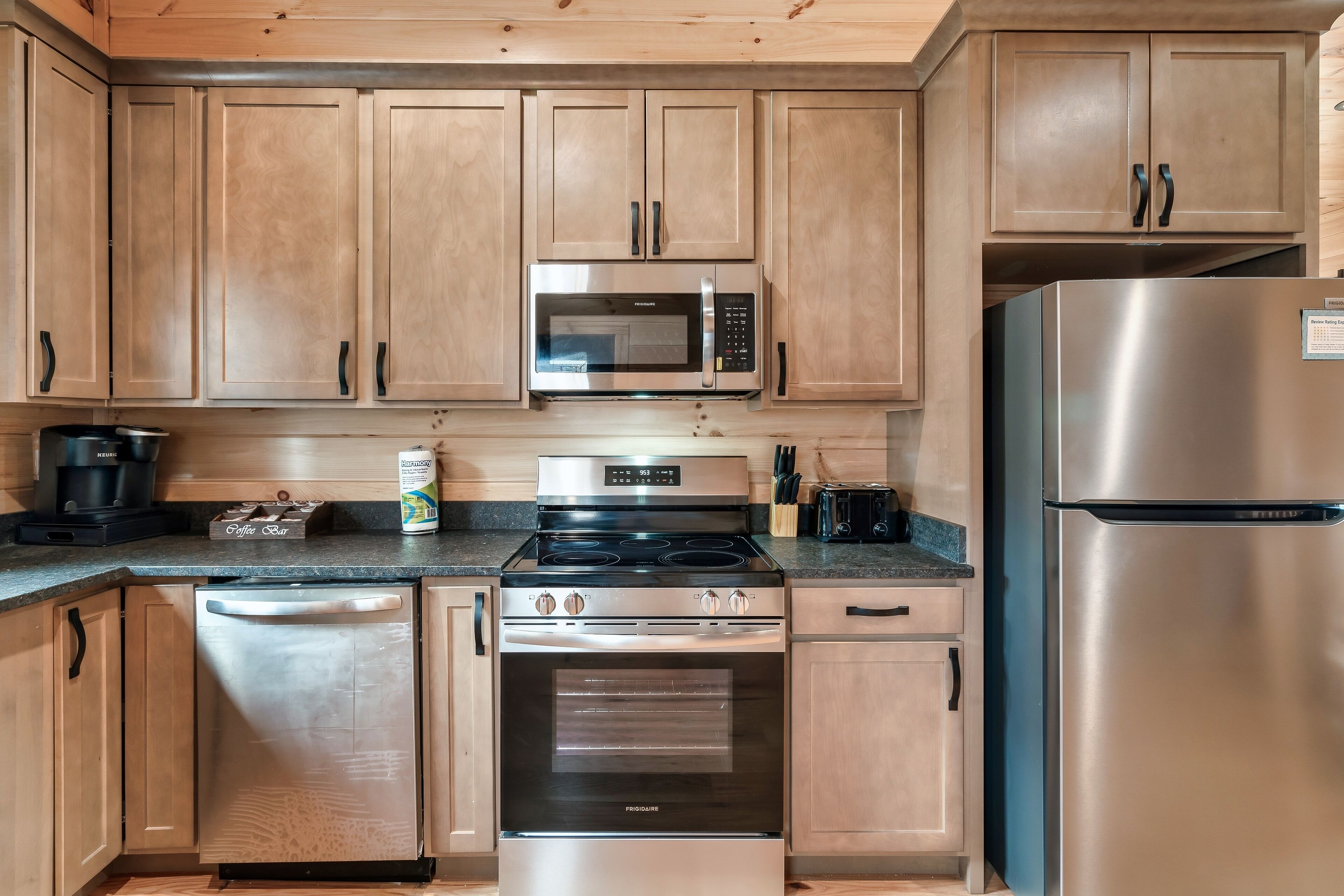 A modern kitchen with wooden cabinets, a stainless steel microwave, a built-in oven, and a refrigerator.