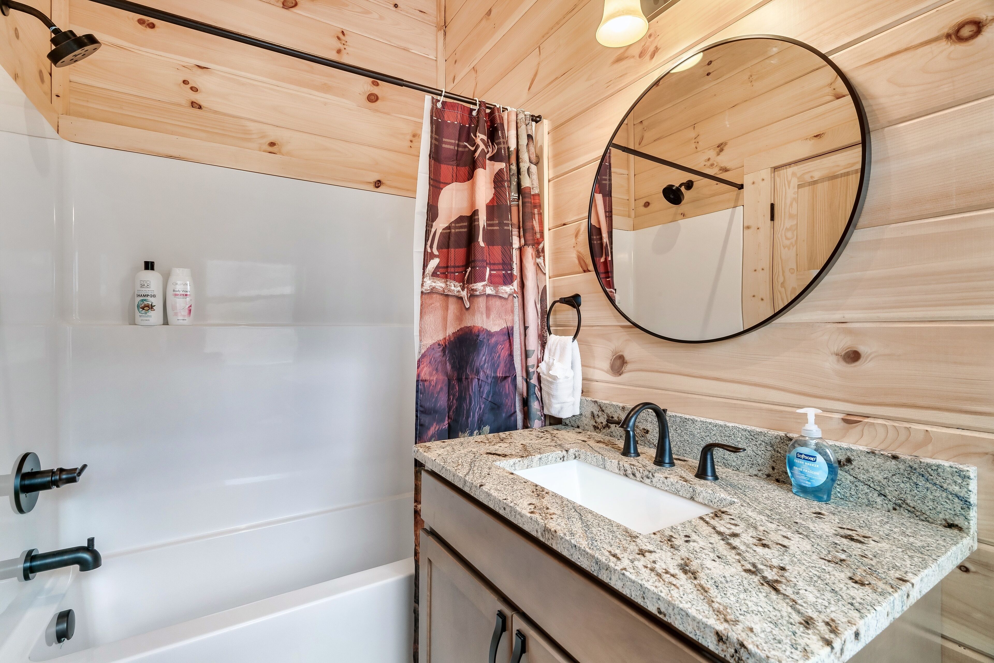 A bathroom with a shower, a sink with a mirror, and toiletries on the counter.