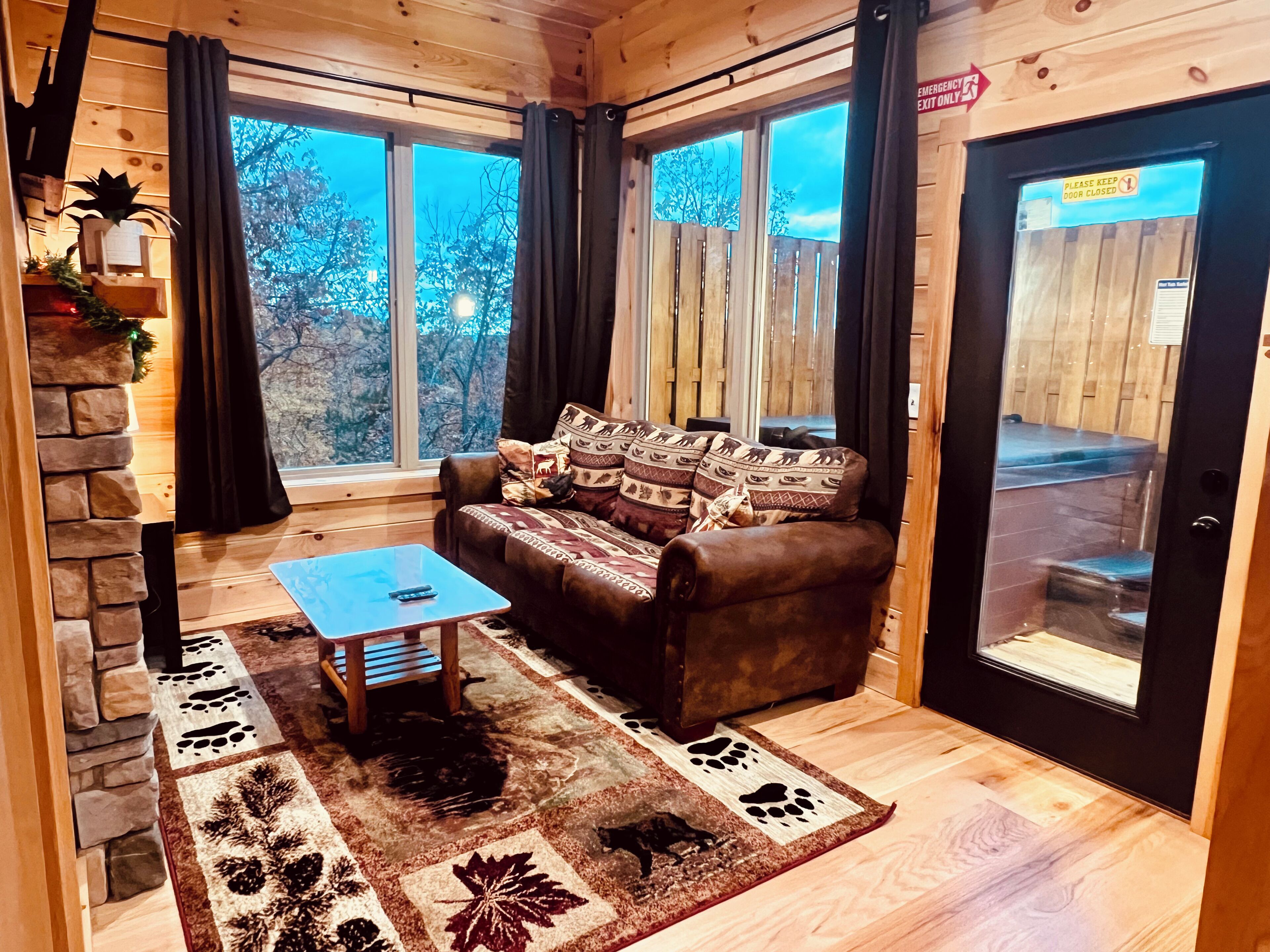 Un intérieur de chalet chaleureux avec un canapé en cuir marron, une petite table en bois et un tapis adapté aux animaux de compagnie.