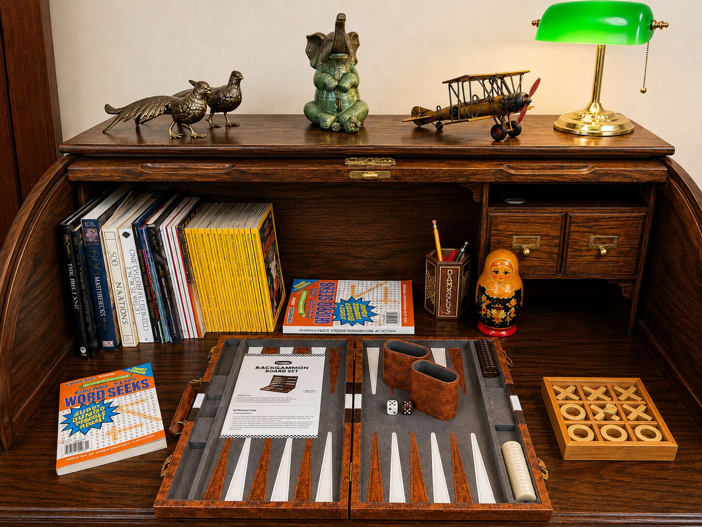 Un bureau en bois, une lampe de bureau verte, une poupée russe (matriochka), un jeu de société et divers livres.