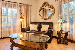 A living room with a leather sofa, a glass coffee table, a mirror, and a lamp. - Historic Home Near Everything w/Gig internet & AC! (Spokane)