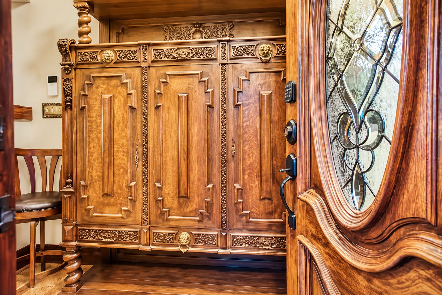 Une porte à deux battants en bois, ornée de sculptures complexes et dotée d’une serrure moderne.