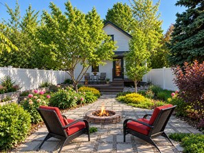 A patio with two wicker chairs, a fire pit, and a white house with a dark roof. - Historic Home Near Everything w/Gig internet & AC! (Spokane)