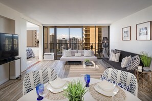 Relax in this stylish living room with a sofa set, dining area, and flat-screen TV, offering a balcony with city views.