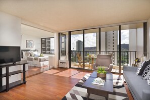 Relax in this stylish living room with a flat-screen TV, sofa, and coffee table, leading to a balcony with city and mountain views.