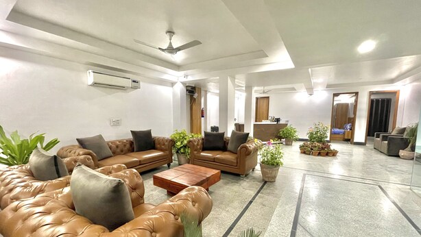 A spacious lobby with leather sofas, a coffee table, and potted plants.