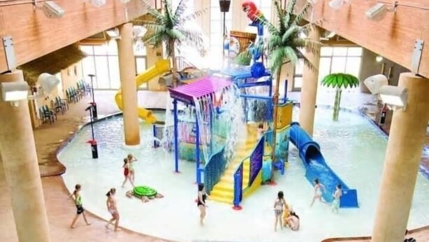 Een overdekt waterpark met verschillende zwembaden, glijbanen en waterspeelzones.
