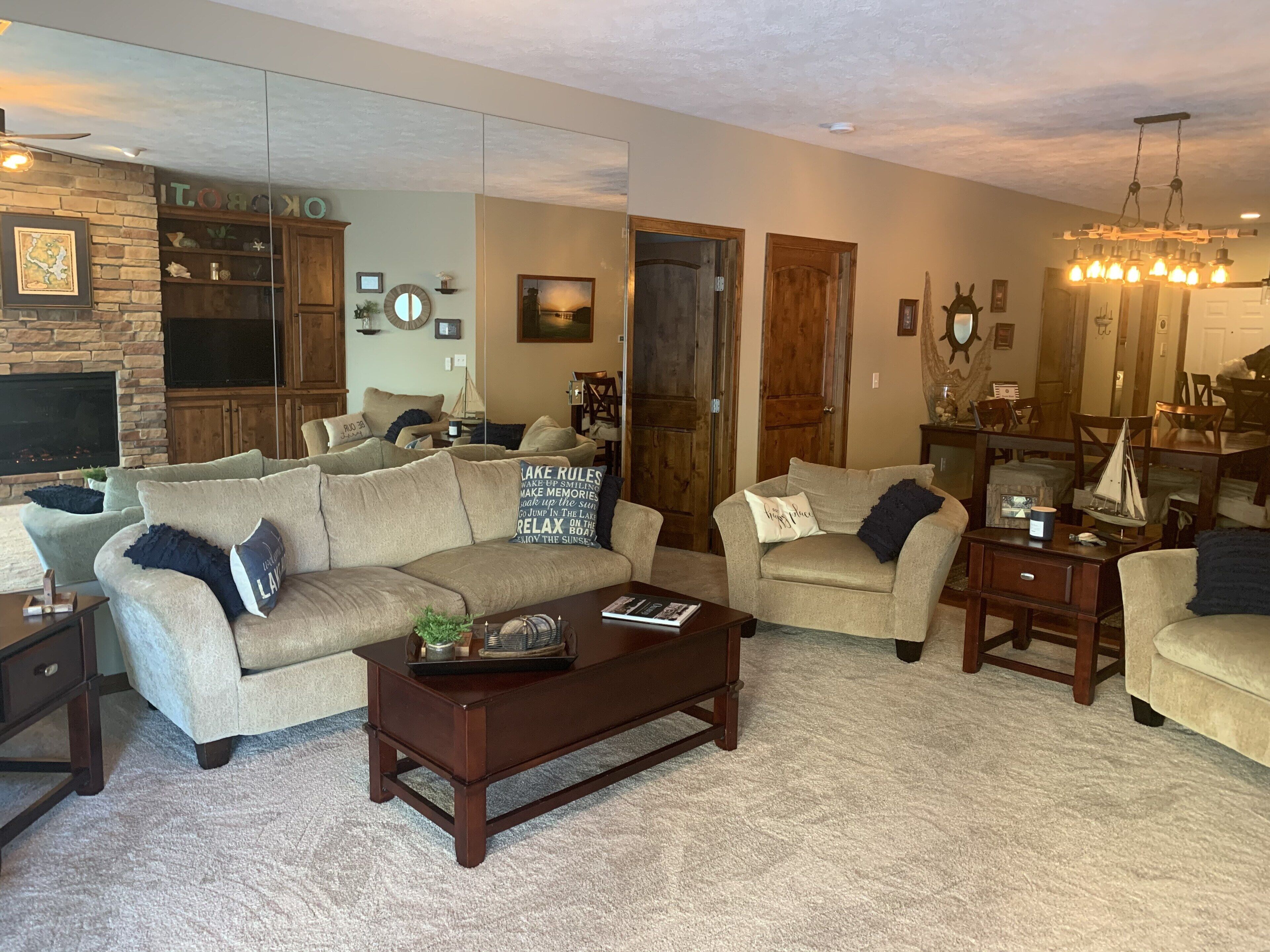 A cozy living room with a fireplace, comfortable sofas, a coffee table, and a chandelier.