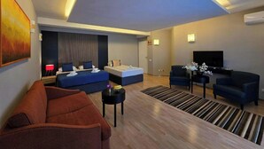 A modern hotel room with a large bed, a sofa, a TV, and a small table. - Hotel Hecco Sarajevo (Sarajevo)