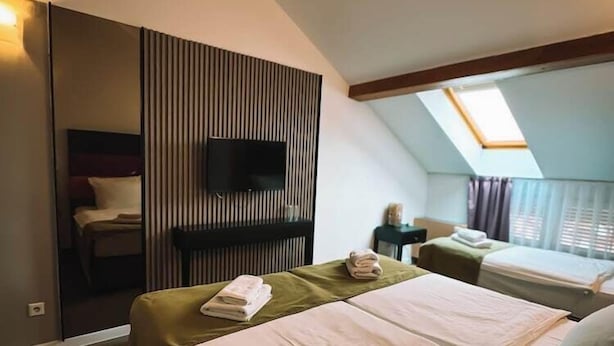 Ett hotellrum med två sängar, en tv, ett takfönster och en spegel.