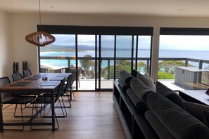 A modern living room with a large sliding glass door leading to a balcony with a view of the sea and mountains. - MOONRISE BINALONG BAY Stunning views (Binalong Bay)