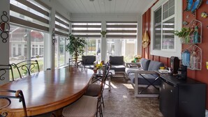 A sunlit dining area with a wooden table, chairs, and a ceiling fan. - Peaceful, Modern Lake Cottage/A Sunny Retreat @ The Cottages on Osoyoos Lake 🌅 (Oliver)