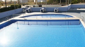 Ein Pool auf dem Dach mit blauer Wasseroberfläche, umgeben von einem weißen Pooldeck und Metallgeländern.