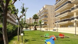 Un quartier résidentiel avec des immeubles à plusieurs étages, une pelouse verdoyante et des jeux pour enfants.