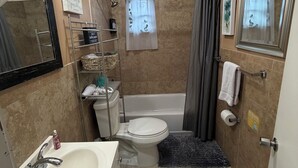 Une salle de bain équipée d’un lavabo, de toilettes, d’une baignoire et d’un rideau de douche.