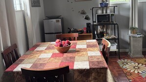 Ruokailutila, jossa on kahdelle katettu pöytä, seinällä oleva kello ja taustalla keittiö.
