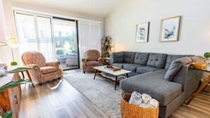 Una sala de estar con un sofá gris, dos sillones, una mesita de centro y una cesta de mimbre.
