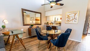Un comedor moderno con una mesa de vidrio, sillas de terciopelo azul y piso de madera.