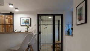 Une cuisine moderne avec un plan de travail en bois, des chaises blanches et un tableau encadré accroché au mur.
