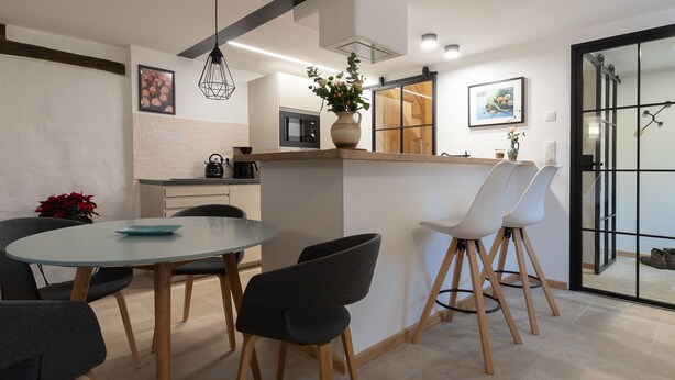 Une cuisine moderne avec un coin repas, comprenant une table ronde, des chaises, un luminaire suspendu et une plante en pot.