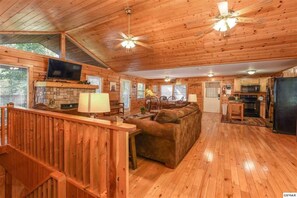 A cabin interior with a living room, dining area, and kitchen.