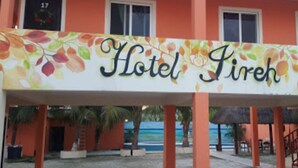 A hotel named "Hotel Firreh" with a colorful sign, orange walls, and a view of the sea. - Hotel Jireh (Bacalar)