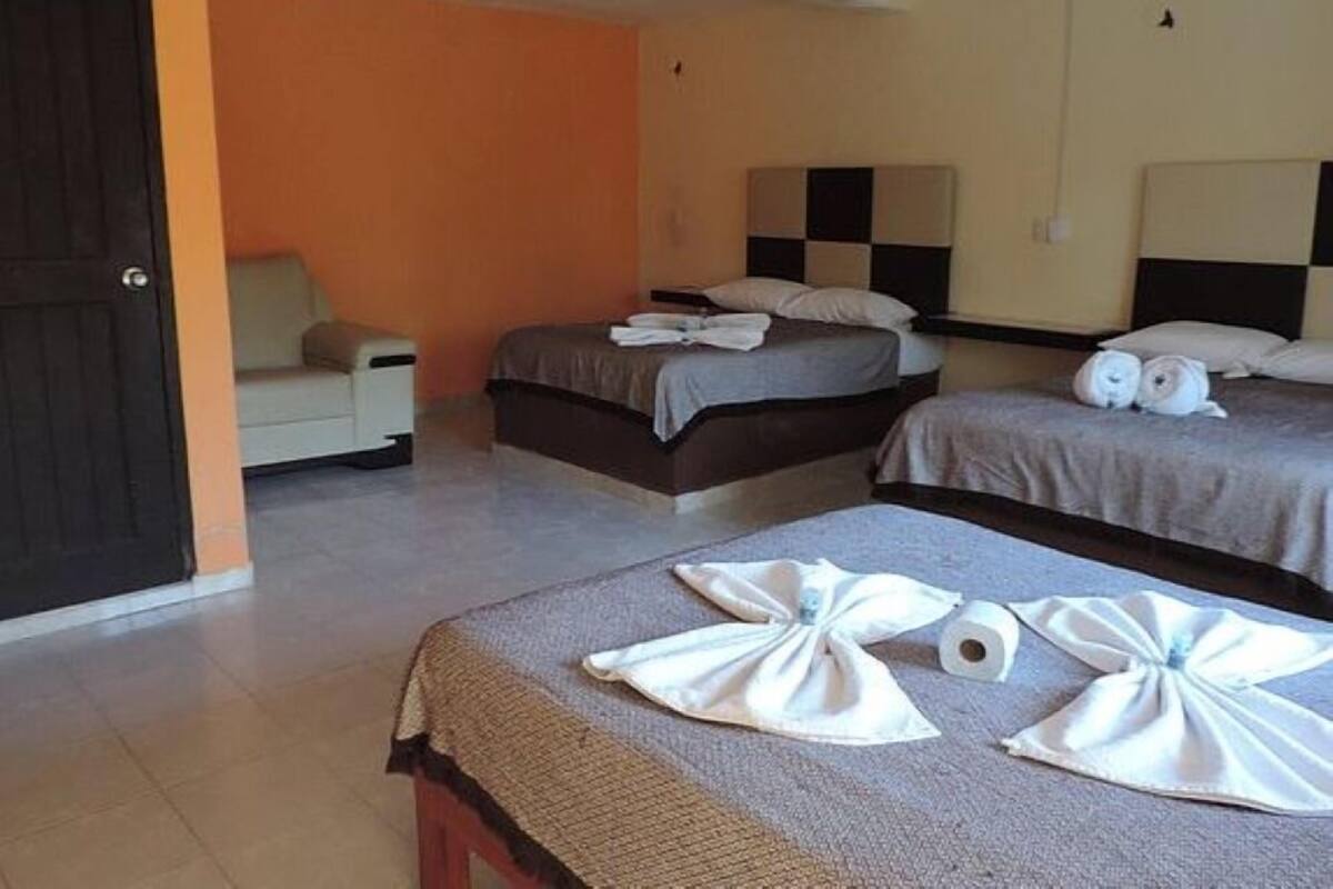 A hotel room with two beds, a chair, and a small table.