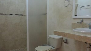 A bathroom with a toilet, sink, and mirror. - Hotel Jireh (Bacalar)