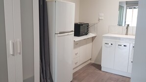 Ett kompakt kök med kylskåp, mikrovågsugn och diskho.