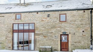 A stone building with a large glass door and windows, a wooden door, and a sign reading "Woodlands Clough". - Woodland's Clough - UK32387 (Don View, near Dunford Bridge)