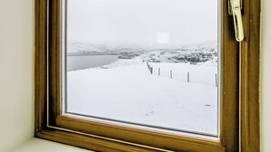 A window with a view of a snowy landscape, including a river and a fence. - Woodland's Clough - UK32387 (Don View, near Dunford Bridge)