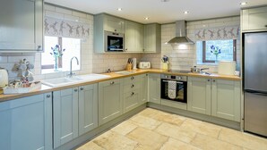 A modern kitchen with grey cabinets, a stainless steel refrigerator, a built-in oven, and a microwave. - Woodland's Clough - UK32387 (Don View, near Dunford Bridge)