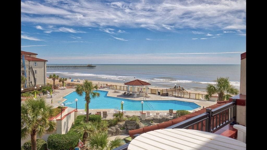 Ein Poolbereich mit Blick auf Strand und Meer.