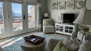 Una sala de estar con un ventanal grande, un televisor, un mueble y un sofá.
