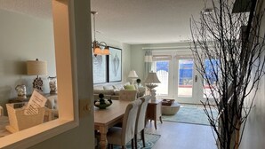 Una sala de estar moderna con comedor, ventanas grandes y vistas al exterior.