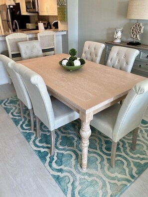 Une table à manger avec six chaises, un saladier rempli de verdure et un tapis à motifs.