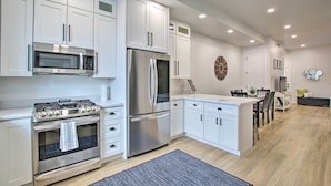 A modern kitchen with white cabinets, stainless steel appliances, and a dining area with a wooden table and chairs.