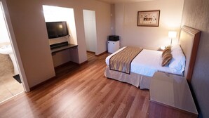 Une chambre d’hôtel équipée d’un lit, d’une télévision, d’un bureau et d’une petite kitchenette.