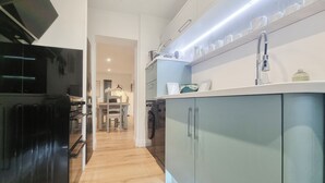 A modern kitchen with a black refrigerator, grey cabinets, and a white countertop. - Mac Shack Cottage - UK32376 (Ashen, near Clare)
