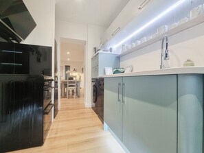 A modern kitchen with a black refrigerator, grey cabinets, and a white countertop. - Mac Shack Cottage - UK32376 (Ashen, near Clare)