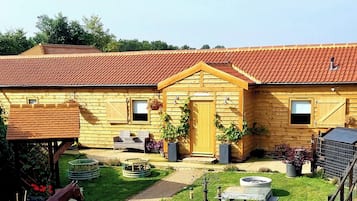 Ein Holzhaus mit rotem Ziegeldach, einer Haustür und einer kleinen Veranda mit Korbmöbeln.