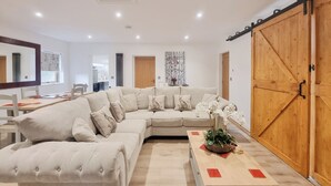 A modern living room with a sectional sofa, a wooden coffee table, and a large sliding barn door. - Mac Shack Cottage - UK32376 (Ashen, near Clare)